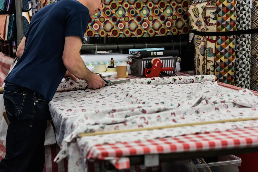 Man cutting fabric on market stall