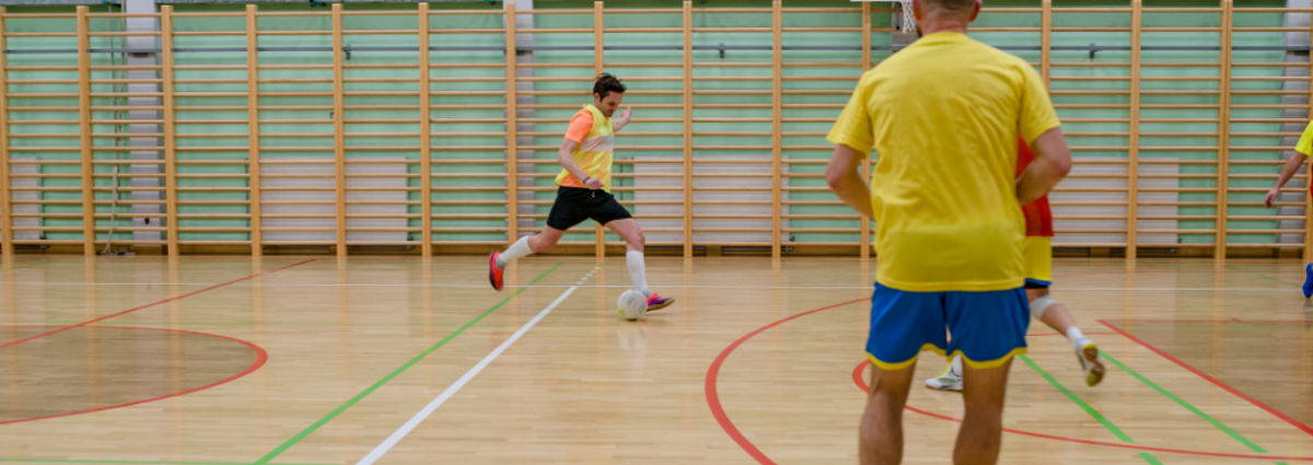People playing football in sports hall. On Your Team: playing sport and lending support. From Safer Chelmsford.