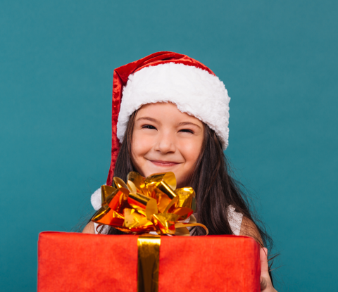 Young Girl In Christmas Hat Holding A Present