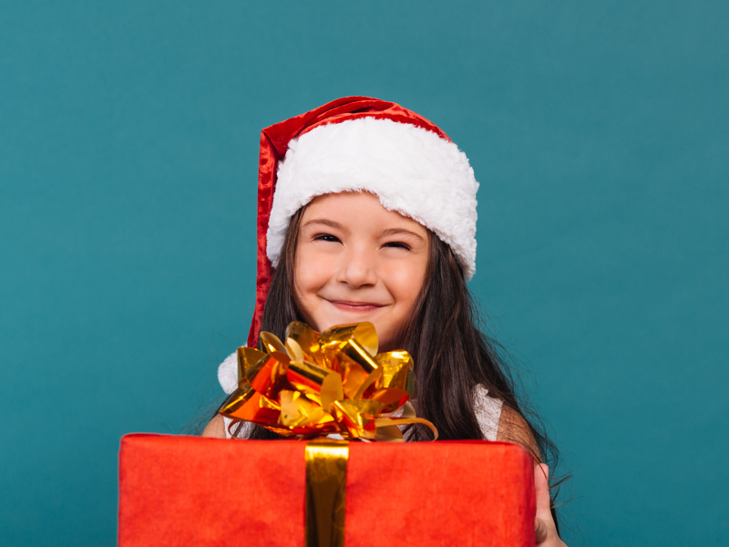 Young Girl In Christmas Hat Holding A Present