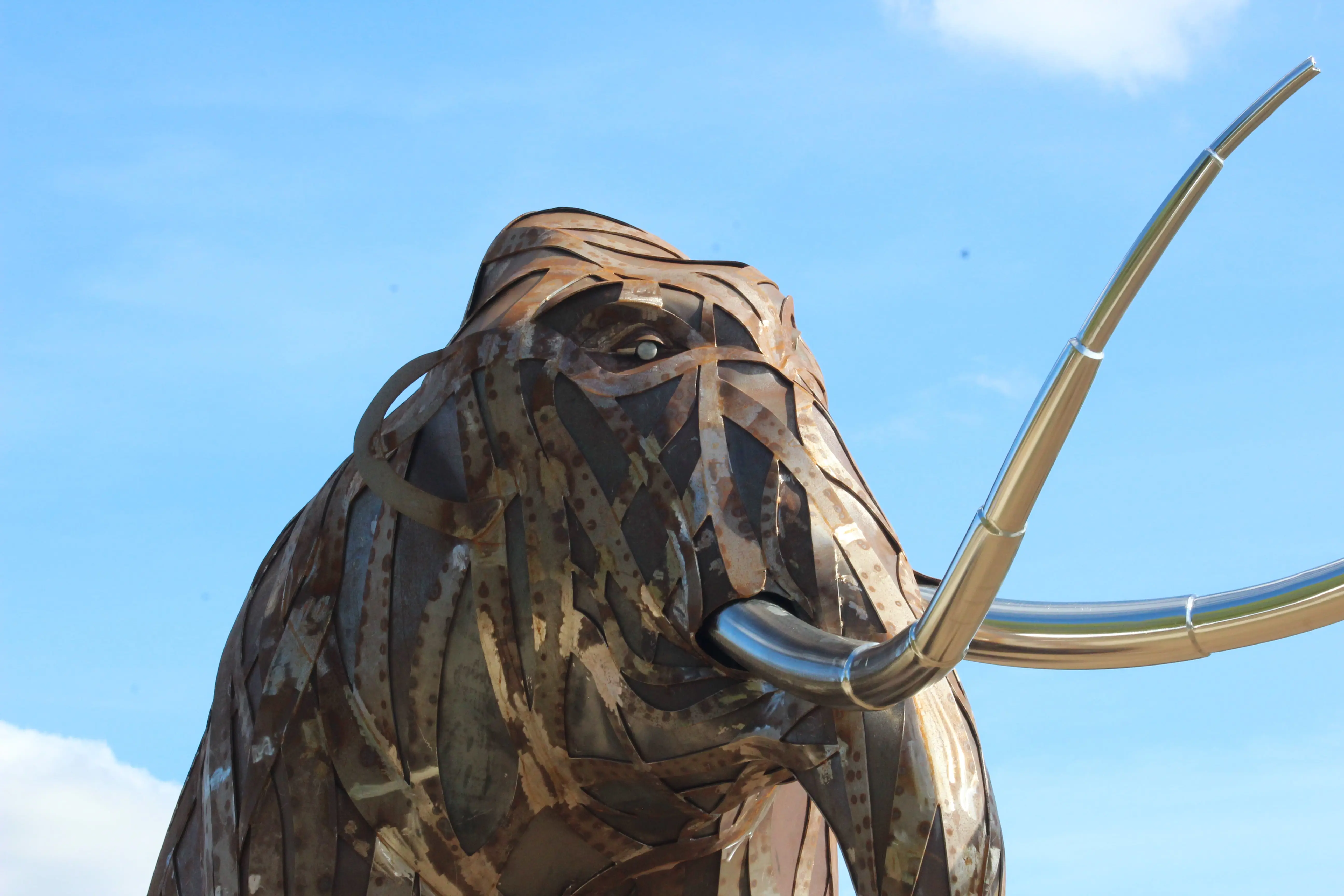 Large metal mammoth sculpture with metalwork skin comprising of a stream of overlapping strips