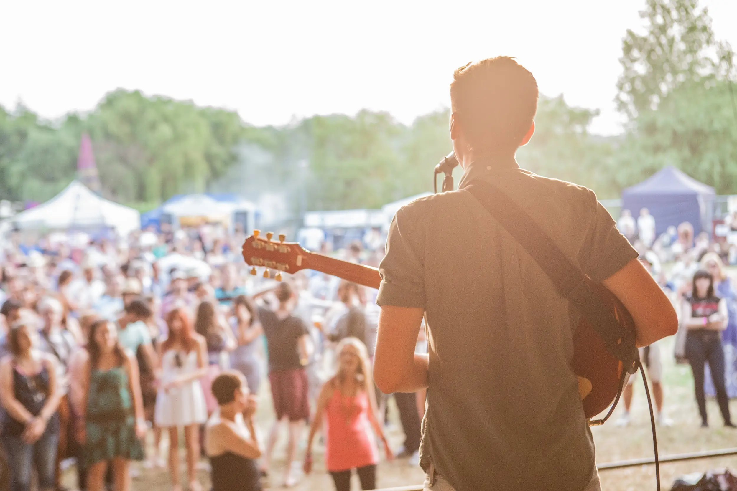 Man singing and playing guitar on stage, looking out at audience