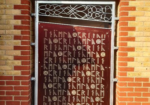 Large panel recessed into brick wall and covered with runes