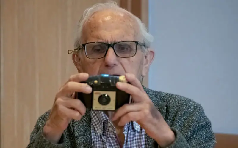 A man looking at a vintage camera. 