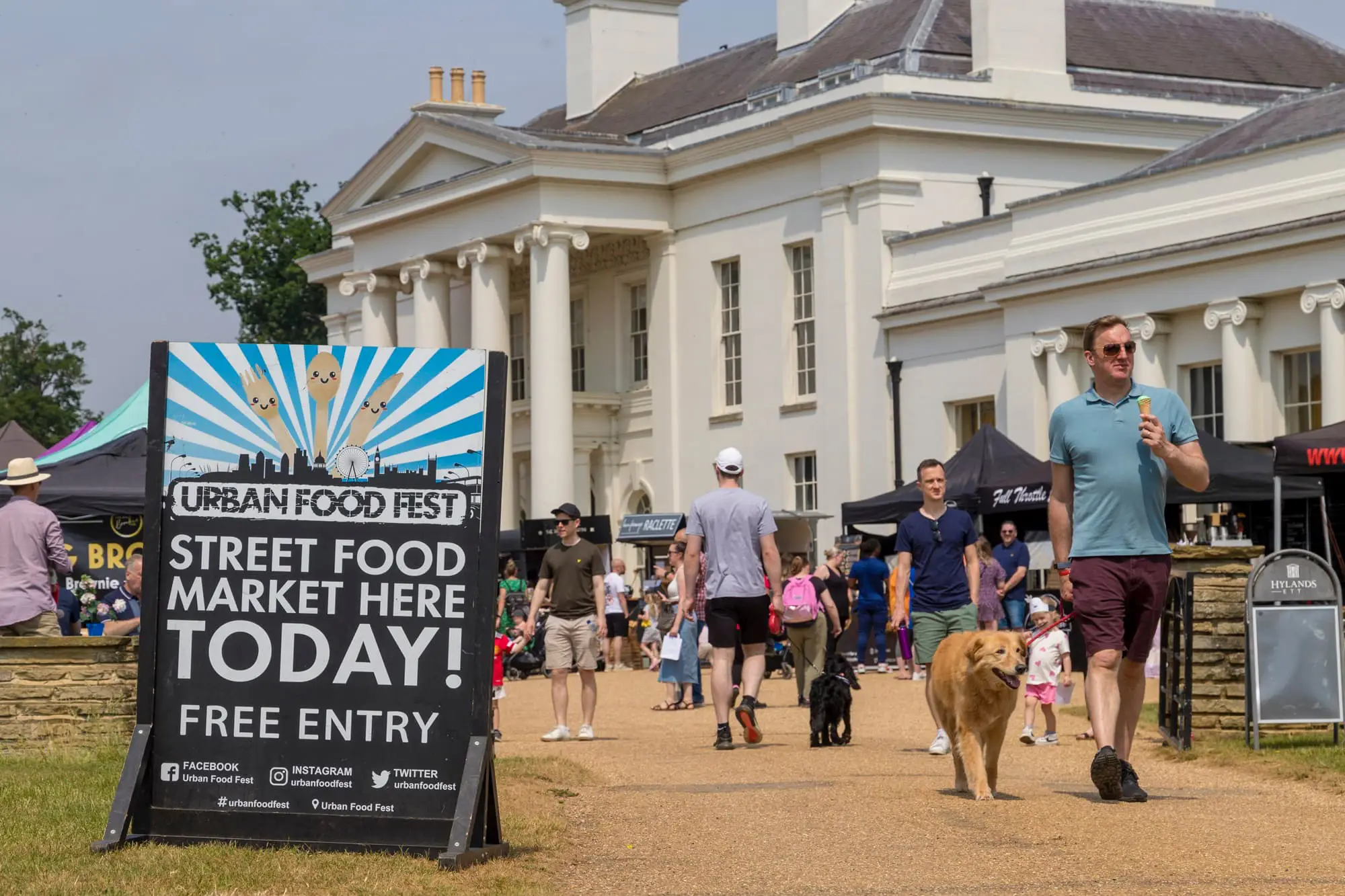 Hylands open day with a large group of people eating food, walking dogs and browsing stalls