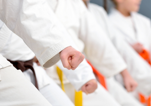 Children lined up wearing white karate suits with various colours of belt