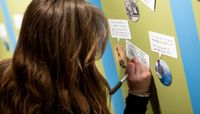 A woman writing down her thoughts about a piece of artwork.  preview